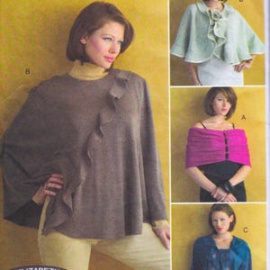 May include: A woman models a brown poncho with a ruffled edge, paired with a yellow turtleneck and cream-colored pants. Additional images show a pink wrap, a green cape, and a blue jacket.