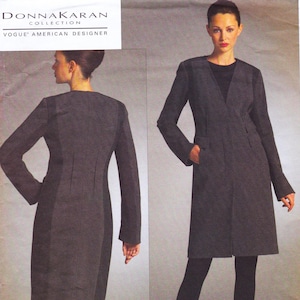 May include: A dark grey, long-sleeved coat with a V-neck and pockets. The image includes a side view of the coat and a front view. The text "DONNA KARAN COLLECTION" and "VOGUE AMERICAN DESIGNER" is visible in the upper left corner.