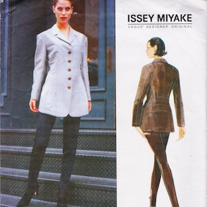 May include: A light grey blazer with brown buttons and black trousers. The blazer has a tailored fit and a classic design. The image also includes the text "ISSEY MIYAKE" and "VOGUE DESIGNER ORIGINAL".