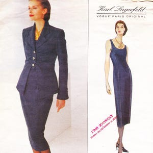 May include: A navy blue skirt suit with a fitted jacket and a pencil skirt. The jacket has a unique button closure and a peplum design. The image also features a navy blue sheath dress. The text "Karl Lagerfeld" and "VOGUE PARIS ORIGINAL" are visible.