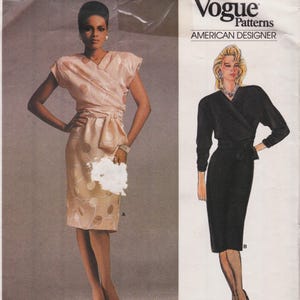 May include: A Vogue Patterns American Designer sewing pattern envelope featuring two dress variations. View A shows a peach-colored wrap dress with a circular pattern and short sleeves. View B shows a solid black long-sleeved wrap dress.