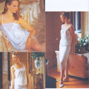 May include: A white satin lingerie set with lace trim. The set includes a camisole top and shorts. The camisole has spaghetti straps and lace detailing at the neckline. The shorts have a matching lace trim. The image shows the lingerie set on a model.