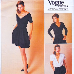 May include: A black dress with a V-neck and short sleeves. The dress features a fitted bodice and a flared skirt. The image also shows a Vogue Patterns label with the text "AMERICAN DESIGNER".