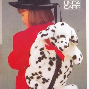 May include: A plush Dalmatian dog with black spots and a red ribbon. The dog is white with black spots and has floppy ears. The image also includes a person wearing a red coat and a black hat. The text "LINDA CARR" is visible in the upper right corner.