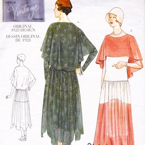 May include: Vintage sewing pattern from 1928, featuring two dress designs with capes. One dress is dark green with a floral pattern, and the other is a white dress with a coral cape and skirt.