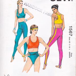 May include: A vintage sewing pattern featuring illustrations of athletic wear. The designs include a teal sports bra and leggings, an orange sports bra and teal shorts, and a yellow sports bra with pink leggings with a yellow stripe. The text "HANCOCK FABRICS" is visible.