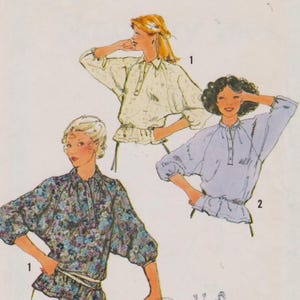 May include: A sewing pattern illustration featuring three blouses with raglan sleeves, button-front plackets, and gathered waistlines. One blouse is shown in a floral print, while the others are solid light colors, labeled with numbers 1 and 2.