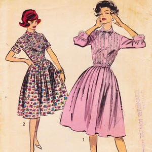 May include: Vintage dress patterns featuring two different dress designs. One dress is a short-sleeved, floral print with a pleated skirt. The other is a long-sleeved, solid pink dress with a pleated skirt and a belt.