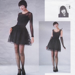 May include: A sewing pattern envelope featuring Anna Sui designs for two black dresses. View A shows a long-sleeved dress with a sheer overlay and lace hem. View B shows a sleeveless dress with a scalloped neckline and lace trim. Both dresses feature a fitted bodice and a flared skirt.