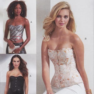 May include: Three strapless corset tops. One is a silver and red quilted pattern, one is a solid black with front hook closures, and one is a cream and gold floral brocade pattern. Each corset features a sweetheart neckline and structured bodice.
