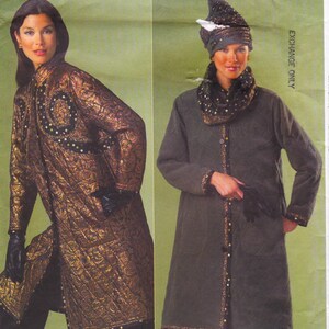 May include: Two women model long coats. One coat is a quilted gold and black pattern with a hood. The other is a long, olive-green coat with a matching hat and scarf. Both coats are button-down.