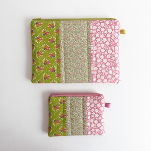 Peut inclure: Deux pochettes en tissu matelassé avec un motif patchwork. La plus grande pochette présente un imprimé floral vert, un imprimé floral avec un fond vert et un imprimé floral rose. La plus petite pochette a le même motif. Les deux ont des fermetures éclair.