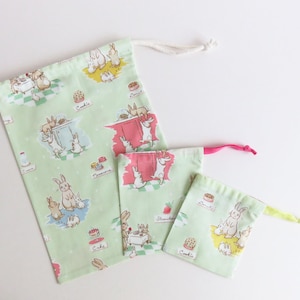 Bolsas con cordón de tela con conejitos y crema de Lauren Nash.