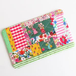 Può includere: Una pochette in tessuto patchwork con uno schema di colori verde, rosa e giallo. La pochette è decorata con un motivo floreale e immagini di topi.