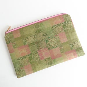 May include: A rectangular pouch with a pink zip and trim. The pouch has a patchwork design in shades of green and pink, with floral and geometric patterns. The zip pull is gold-toned.