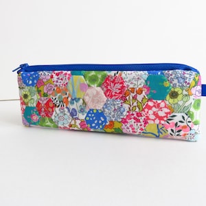 May include: A blue zippered pencil case with a patchwork design of colourful hexagonal fabric pieces featuring floral patterns.