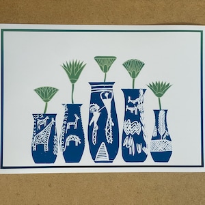 May include: A print featuring six blue vases with white illustrations of animals and patterns. Each vase holds a green flower. The print has a white background with a blue and green border. The artwork is on a light brown surface.