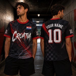 Op de afbeelding: Een zwart en rood sport-T-shirt met de tekst Croatia op de voorkant en een kleine Kroatische vlag, en de tekst Your Name boven het nummer 10 op de achterkant. Het shirt heeft een ruitpatroon, rode randen bij de mouwen en het nummer 10.