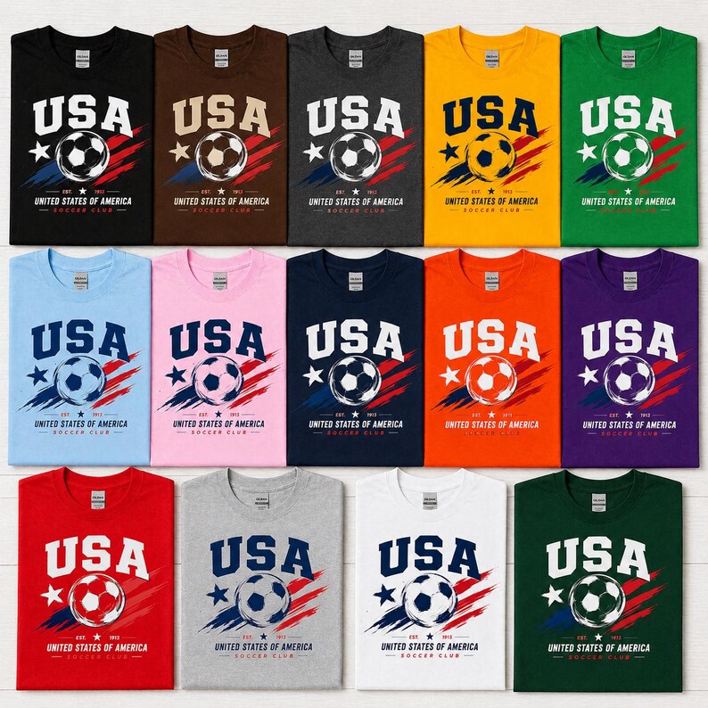 Puede incluir: Una colecci&oacute;n de camisetas de varios colores, cada una con la palabra "USA" en letras blancas en negrita sobre un gr&aacute;fico de bal&oacute;n de f&uacute;tbol. Debajo del gr&aacute;fico est&aacute; el texto "UNITED STATES OF AMERICA SOCCER CLUB".