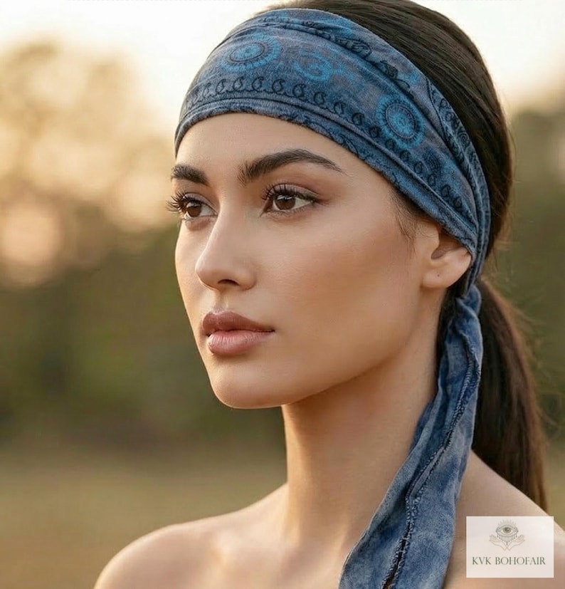 May include: A blue patterned headband with a matching tie. The headband is worn around the head and tied at the back. The design features circular and paisley-like patterns. The headband is made of a soft, possibly cotton, material.