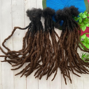 Peut inclure: Deux ensembles de dreadlocks synthétiques ombrés brun et noir. Les dreadlocks mesurent environ 50 cm de long et sont faites d'un matériau synthétique doux.