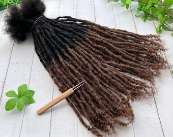 May include: A set of black and brown ombre synthetic dreadlocks with a wooden dreadlock tool. The dreadlocks are long and wavy.
