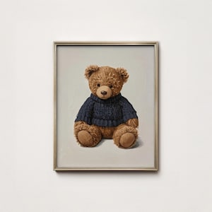Könnte beinhalten: Gerahmter Druck mit einem braunen Teddybären, der einen marineblauen Pullover trägt. Der Bär sitzt mit ausgestreckten Armen und Beinen. Das Kunstwerk ist vor einem hellgrauen Hintergrund platziert und in einem goldfarbenen Rahmen gerahmt.