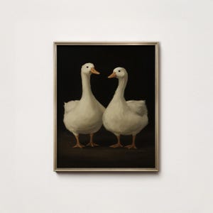 以下が含まれることがあります： 暗い背景に2羽の白いガチョウが描かれた額入りのアートプリント。ガチョウは柔らかな筆致で描かれ、白い羽とオレンジ色のくちばしが表現されています。アートワークは金色のフレームに収められています。