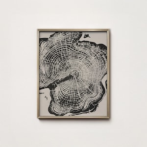 Puede incluir: Impresión en blanco y negro enmarcada de una sección transversal de árbol, mostrando anillos de crecimiento detallados. La obra de arte está encerrada en un marco dorado, ofreciendo una estética natural y minimalista. Ideal para la decoración del hogar.