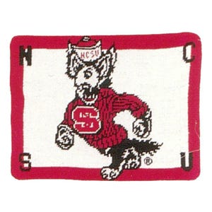 May include: A rectangular, red-bordered, needlepoint design featuring the NC State Wolfpack mascot. The wolf is depicted in red and white, wearing a sweater with a large "S". The letters "NCSU" are on the wolf's hat.