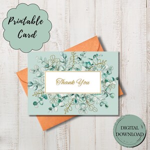 Pode incluir: Um cartão de agradecimento imprimível com fundo azul claro e uma caixa de texto com moldura dourada que diz "Thank You". O cartão é decorado com folhas de eucalipto verdes e douradas e vem com um envelope laranja. As palavras "Printable Card" e "Digital Download" também são visíveis.