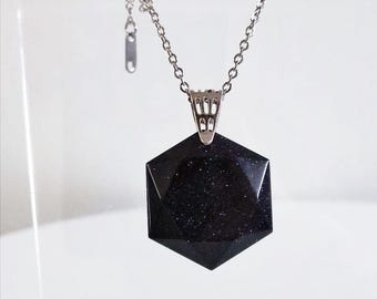 May include: A silver chain necklace with a hexagonal pendant made of dark blue, sparkly stone.