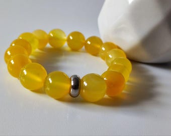 May include: A yellow beaded bracelet with a silver metal bead accent. The bracelet is made of round, smooth beads.