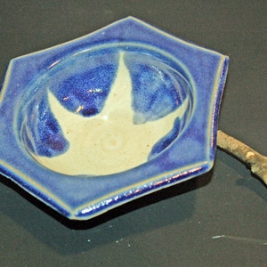 May include: A blue and white ceramic bowl with a starburst design. The bowl is shaped like a star and has a slightly raised rim.