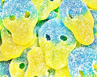 May include: Close-up of colorful, sugary skull-shaped candies. The candies are a mix of yellow and blue, with a dusting of white sugar. The skull shapes have eye and nose openings, creating a playful and festive appearance. A sweet treat.