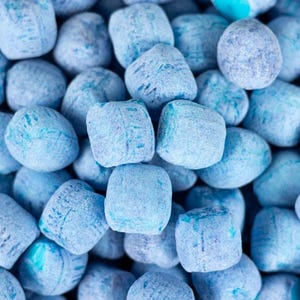 May include: A close-up of a pile of blue candy. The candy is round and has a slightly textured surface.