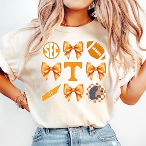 A woman wearing a white t-shirt with various football and bow icons printed on it.