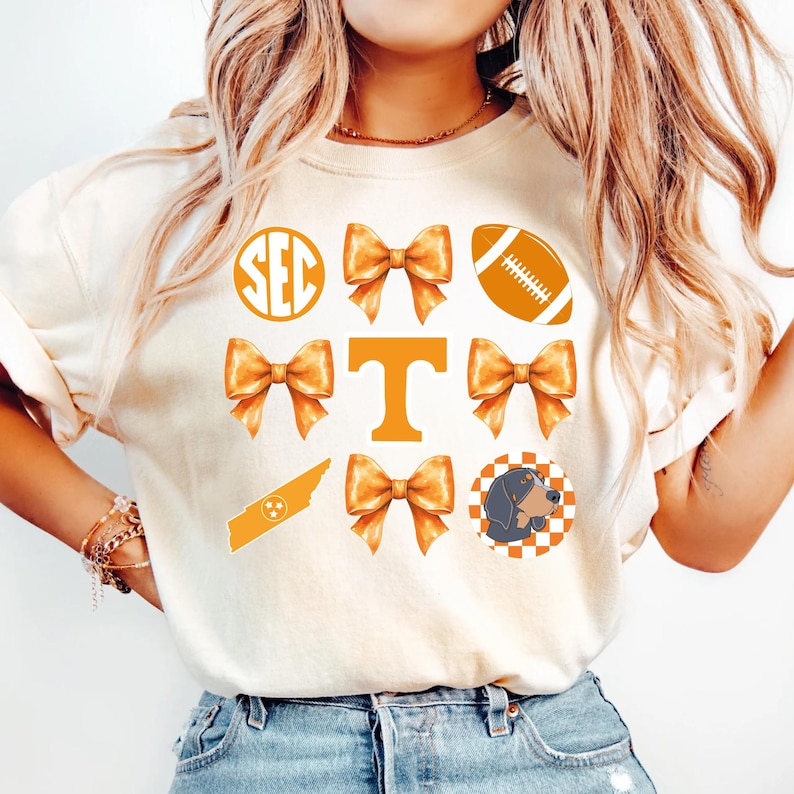 A woman wearing a white t-shirt with various football and bow icons printed on it.
