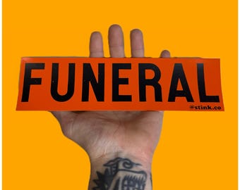 Puede incluir: Pegatina naranja con la palabra "FUNERAL" en letras negras y el texto "@stink.co" en letras negras más pequeñas.
