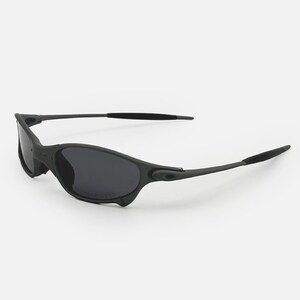 May include: Black sunglasses with dark grey lenses. The sunglasses have a sleek, sporty design with a matte finish. The temples are thin and extend to curved ear pieces. The lenses are polarized.