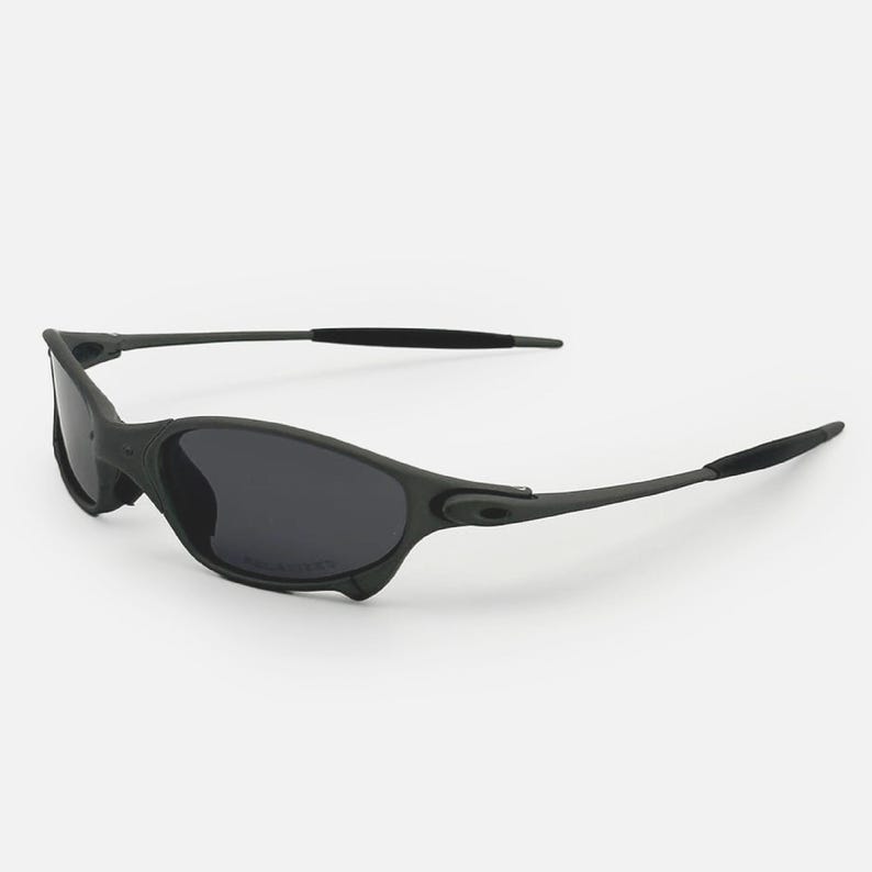 May include: Black sunglasses with dark grey lenses. The sunglasses have a sleek, sporty design with a matte finish. The temples are thin and extend to curved ear pieces. The lenses are polarized.