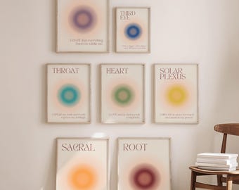 Könnte beinhalten: Neun gerahmte Kunstdrucke mit verschwommenen, farbenfrohen kreisförmigen Designs, die jeweils mit einem Chakra-Namen beschriftet sind: Krone, Drittes Auge, Hals, Herz, Solarplexus, Sakral und Wurzel. Die Drucke haben inspirierenden Text. Ein Holzstuhl und Bücher sind im Bild.
