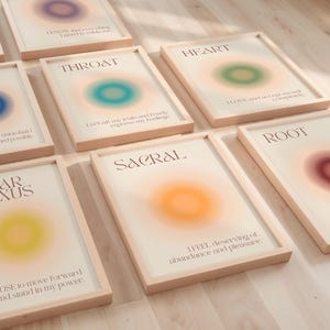 Peut inclure: Plusieurs impressions d'art encadrées avec des motifs d'aura colorés. Chaque impression présente un nom de chakra, une affirmation et un dégradé de couleurs flou. Les cadres sont en bois clair, et l'esthétique générale est apaisante.
