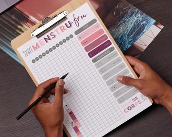 May include: A white clipboard with a wooden frame and a silver clip. The clipboard has a grid pattern and text that says "SUIVI DE MES MENSTRU-fru" and "ECOUTE TON CORPS". There are also sections for "FLUX" and "SYMPTOMES".