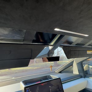 以下が含まれることがあります： サンルーフと十字架がぶら下がったリアビューミラーが付いた黒い車のインテリア。車は黒い革張り内装と白いダッシュボードです。