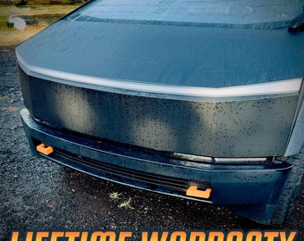 May include: A close-up of the front of a black vehicle with a unique angular design. It features a light bar and orange accents. The text "LIFETIME WARRANTY" is displayed in orange and yellow at the bottom of the image.