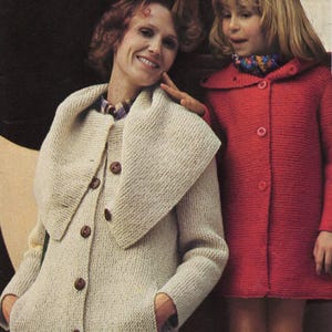 May include: A woman and child wearing knitted coats. The woman's coat is light beige with a large collar and brown buttons. The child's coat is red with a rounded collar and matching buttons. Both coats have pockets.