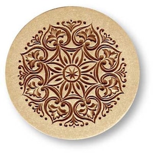 May include: A round, wooden coaster with a brown, intricate, floral design. The design is symmetrical and features a star in the center.
