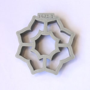 May include: A gray, 3D printed, star-shaped cookie cutter with a detailed design and the number "1671.1" printed on the top.