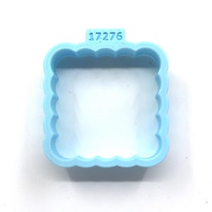 May include: A light blue plastic cookie cutter shaped like a square with a scalloped edge. The cutter has the number "17276" printed on the top.